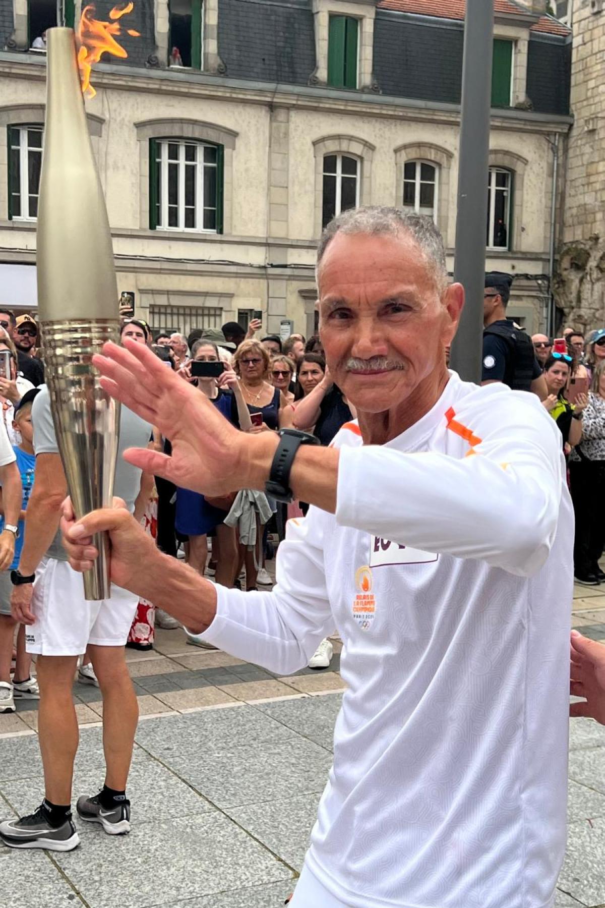 Le major (ER) Kenane, président de l'association des Harkis Supplétifs et Rapatriés en Meuse porte la Flamme Olympique dans les rues de Verdun, le samedi 29 juin 2024 @ André KENANE / AHSRM